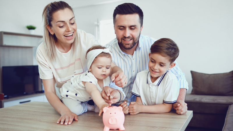 Young family teaching children about saving with a piggy bank, symbolising the importance of creating a cash flow budget in Croydon