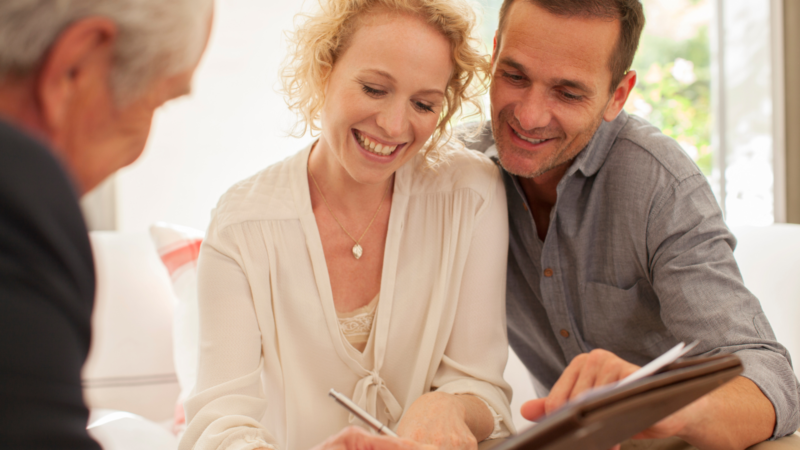Smiling couple reviewing paperwork with a financial advisor, representing support with changing super funds