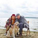 Older couple walking their dog on the beach, symbolising a relaxed lifestyle made possible with a retirement planner in Melbourne.