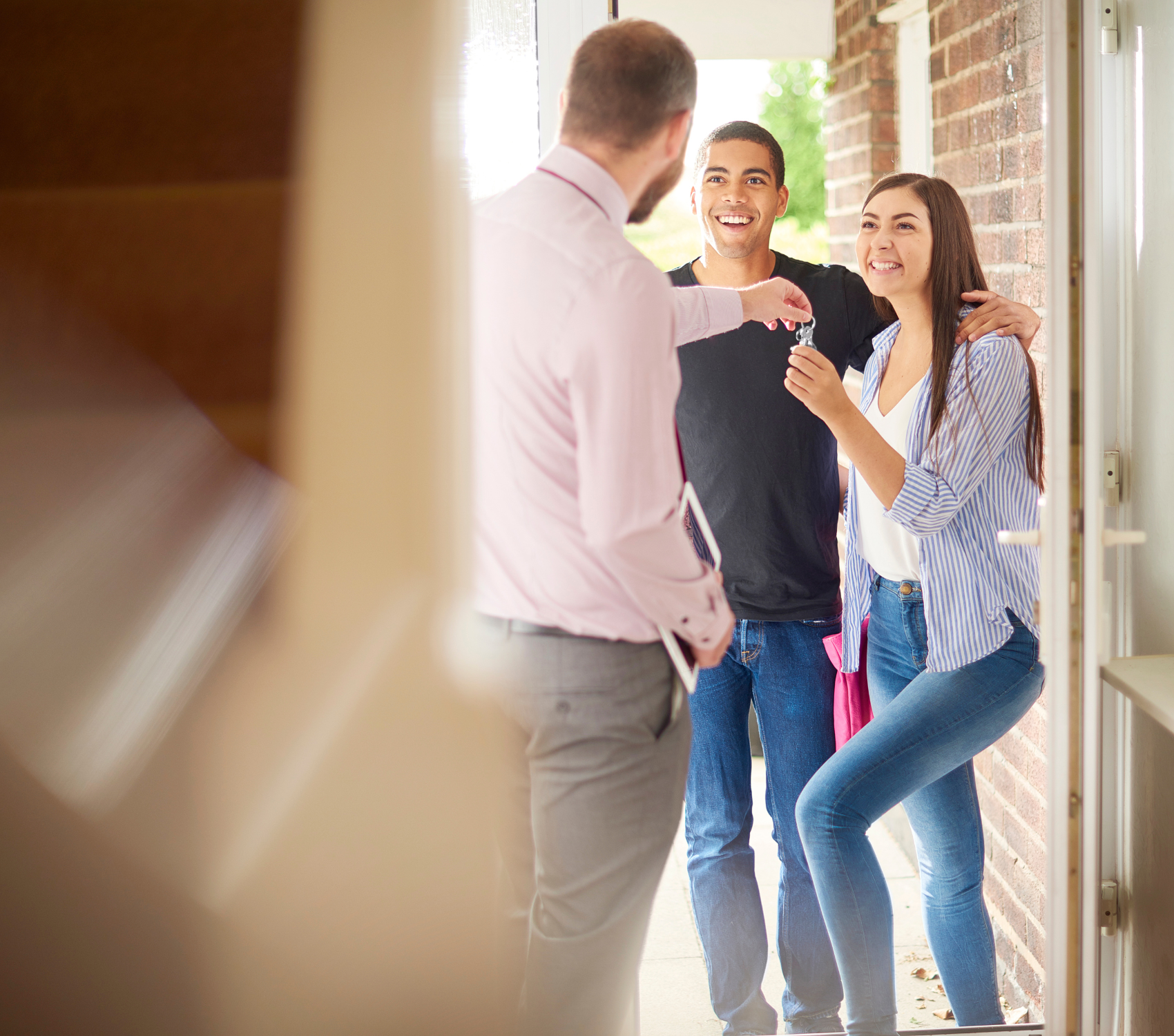 Happy couple receiving house keys from an agent, representing the use of borrowed funds to invest in property