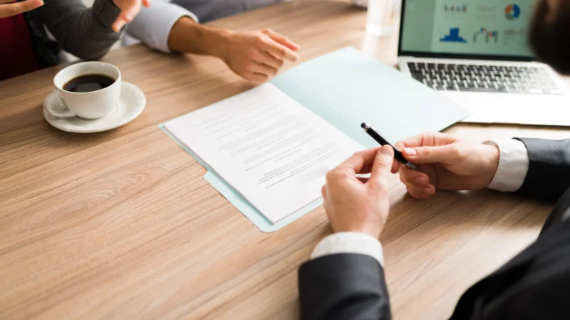 Financial advisor meeting with clients at a desk, reviewing documents and investment reports